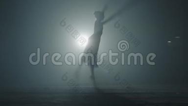 在黑暗中用灯光和烟雾训练勤奋的年轻优美的芭蕾舞演员舞蹈元素